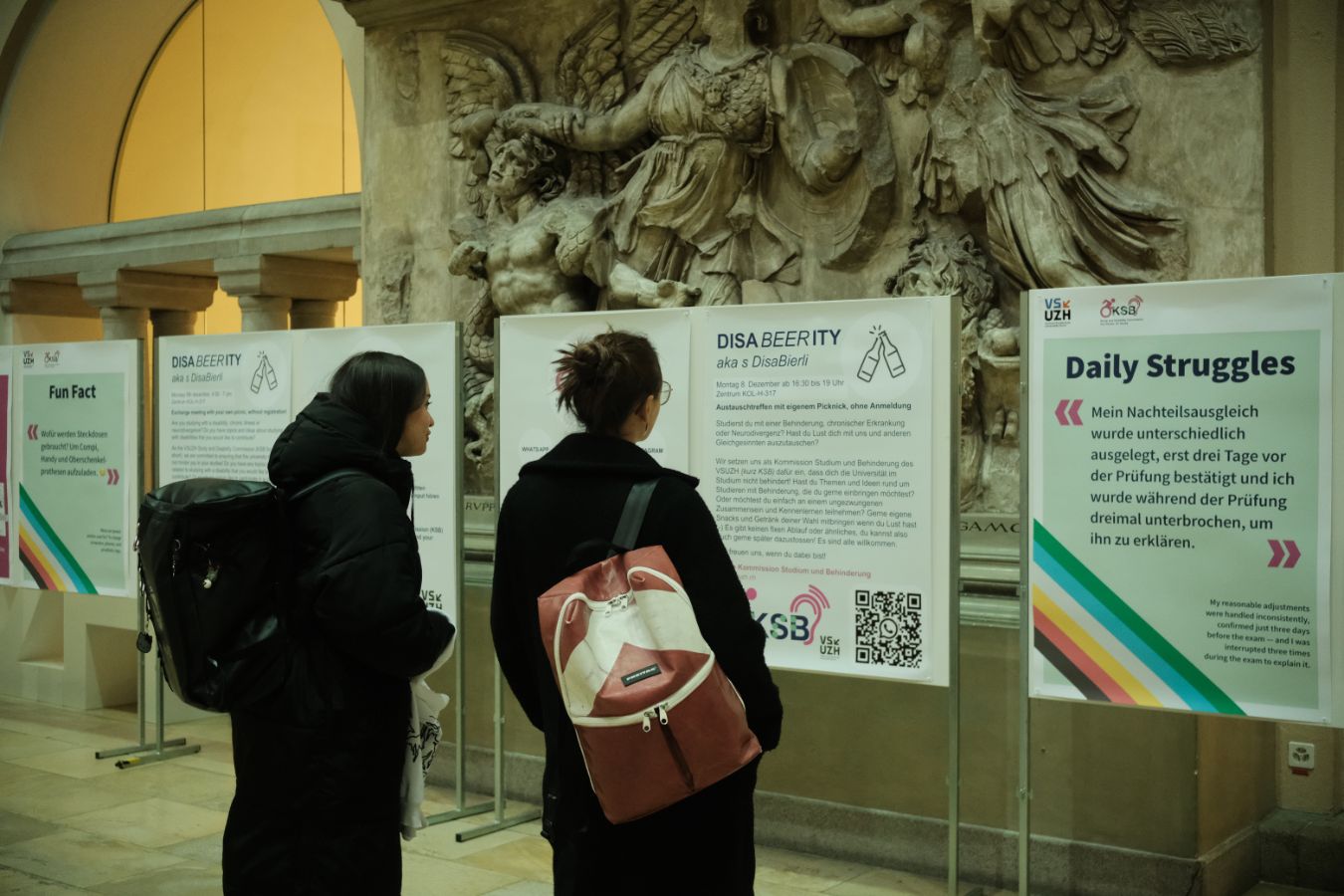 Plakatausstellung: Zwei Personen stehen vor Plakaten der Plakatausstellung zu Disability Awareness und lesen die Texte im Lichthof der UZH.